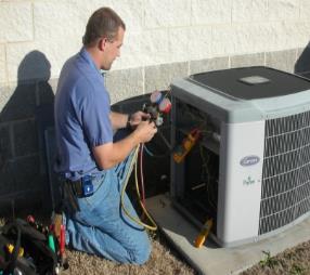 A Colony technician checking refrigerant pressure on a Carrier AC unit in Plano
