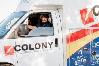 Two smiling Colony technicians in a truck on their way to a service call in Frisco