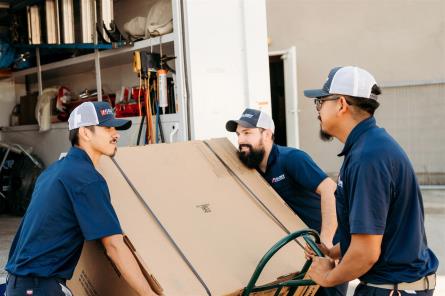 Team of AC experts lifting new AC unit onto one of Colony's fully-stocked service trucks
