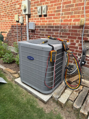 An outdoor Carrier central AC condenser with HVAC diagnostic equipment hooked up to it.